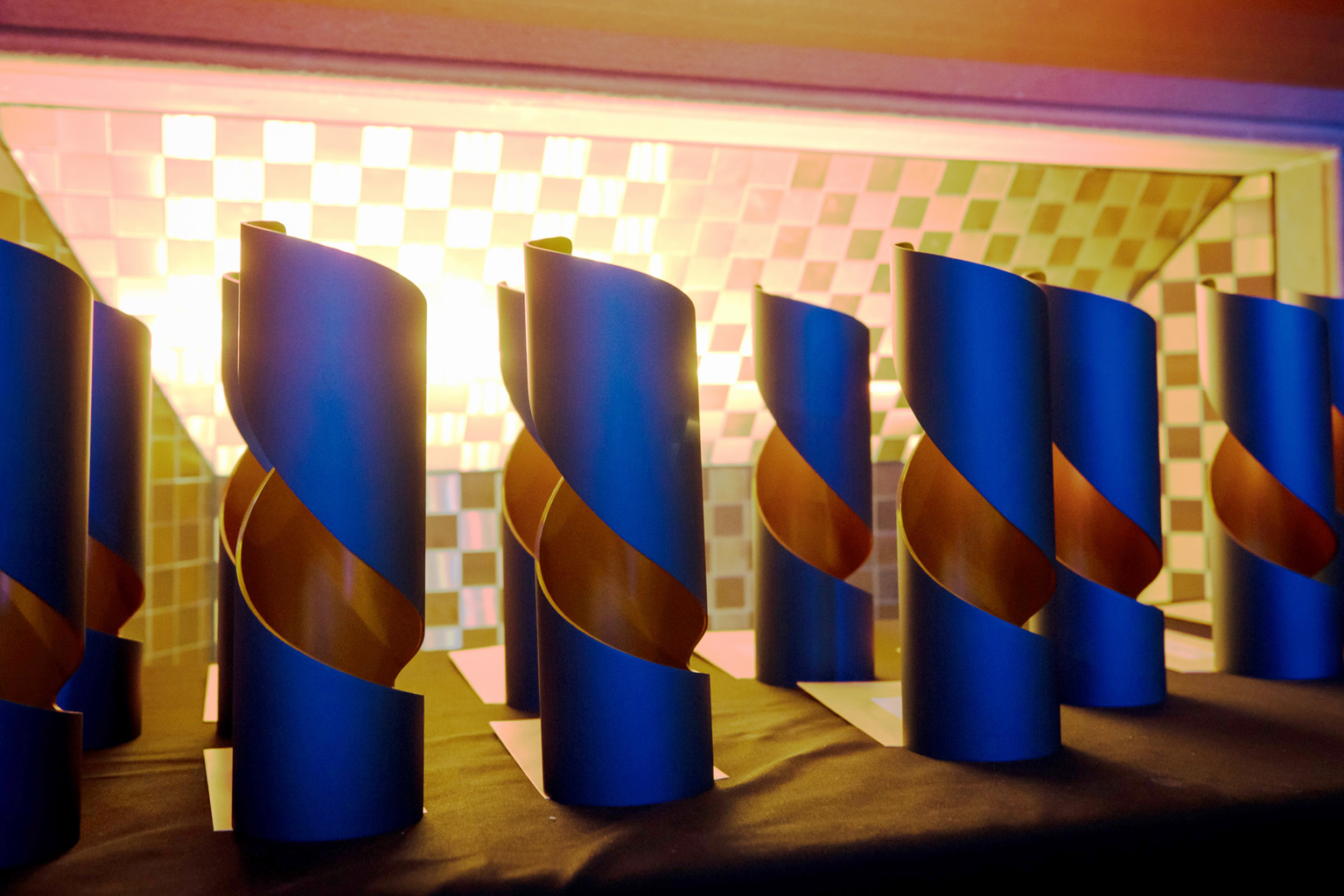 11 Media Awards trophies sit on a table backlit. 